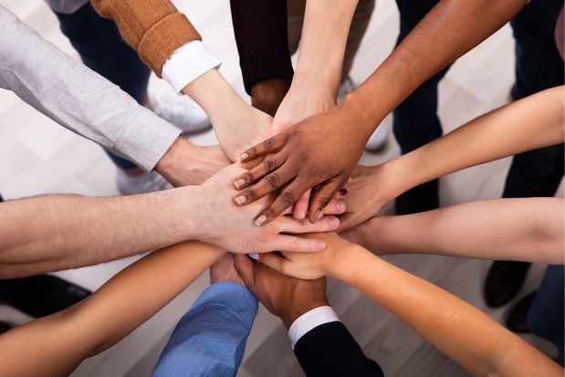 diverse group of people joining hands